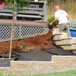 Workers covering the weed barrier with mulch